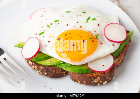 Toast de pain de grains entiers sains avec de l'avocat, œuf frit et radis Banque D'Images