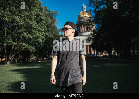 Bel homme marche touristique sur la pelouse près de la Cathédrale Saint Isaac à Saint-Petersbourg en journée ensoleillée. Banque D'Images