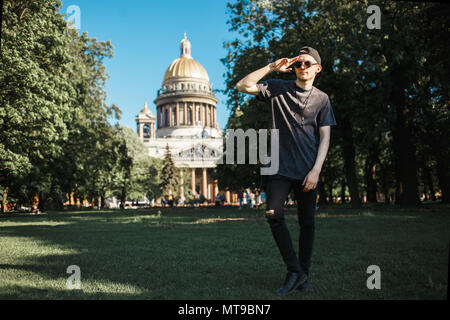 Bel homme marche touristique sur la pelouse près de la Cathédrale Saint Isaac à Saint-Petersbourg en journée ensoleillée. Banque D'Images