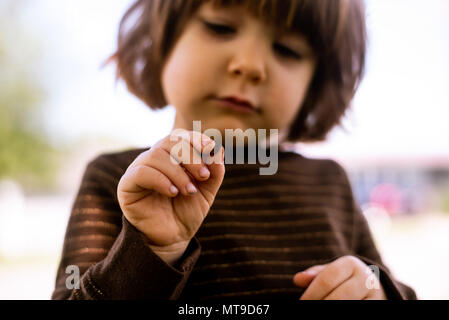 Un bébé fille tenant un bug dans ses mains. Banque D'Images