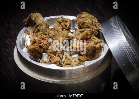 Metal grinder avec de la marijuana isolé sur une table en bois noir Banque D'Images