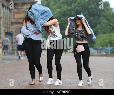 Les personnes utilisant leur veste pour mettre à l'abri d'une douche à effet pluie à l'Alexandra Palace, Londres. Banque D'Images