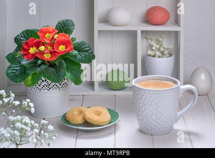 Tasse de café et des biscuits sur la table en bois blanc avec décorations de printemps et primrose rouge Banque D'Images