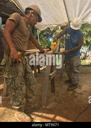 KOSRAE (États fédérés de Micronésie (19 avril 2017) 3ème classe Métallos Timothy Vincent, de Minneapolis, Minnesota, et la construction locale apprenti, Arthur Eugene, couper du bois pour fabriquer des portes d'intérieur au cours de la Construction Navale du Bataillon mobile (NMCB) 1 Projet de clinique de santé Walung à Kosrae (États fédérés de Micronésie, le 19 avril, 2017. 1 NMCB est déployée avant d'exécuter la construction, l'aide humanitaire et l'aide étrangère, les opérations spéciales des services de soutien au combat, et le théâtre de la coopération en matière de sécurité dans l'appui de United States Pacific Command. Banque D'Images