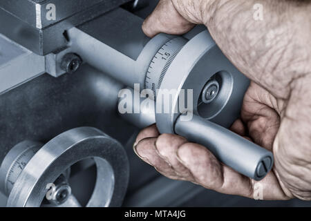 Close-up de roues de contrôle de l'avance sur une machine-outil. Détail d'une sale main sur le bouton de métal avec un vernier pour une mesure exacte. Banque D'Images