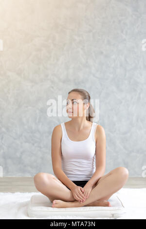 Young caucasian woman practicing yoga très attrayant, assis en Padmasana faisant du yoga ou de l'exercice pose Lotus ou namaste poser. Travailler sur son lit. Banque D'Images