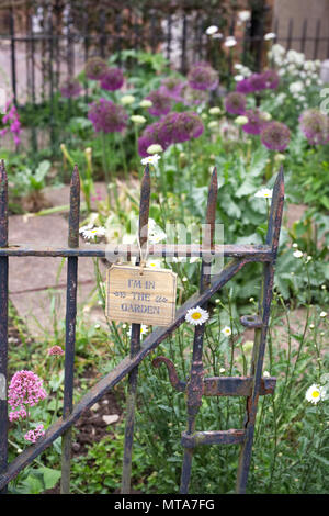 'Je suis dans le jardin" signe sur une vieille grille rouillée dans un jardin à l'avant. Banque D'Images