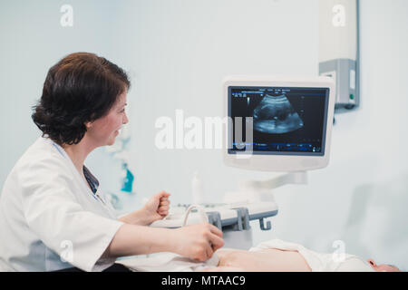 Femme enceinte à ultrasons à coups de son bébé en pleine croissance a montré par son médecin lors de l'examen médical Banque D'Images