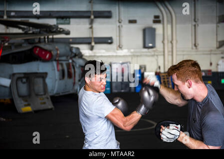 Le Golfe Arabique (20 avril 2017) l'Aviation maître de Manœuvre (manutention) Airman Lorenzo Resendiz et aviation maître de Manœuvre (manutention) Airman Samuel Holland spar à bord du porte-avions USS George H. W. Bush (CVN 77) (GHWB). GHWB est déployée dans la zone 5e flotte américaine des opérations à l'appui d'opérations de sécurité maritime visant à rassurer les alliés et les partenaires, et de préserver la liberté de navigation et la libre circulation du commerce dans la région. Banque D'Images