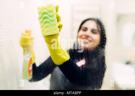 Gants de ménage nettoie vitre avec un spray de nettoyage, hôtel bains intérieur sur l'arrière-plan. Femme de ménage professionnelle, Banque D'Images