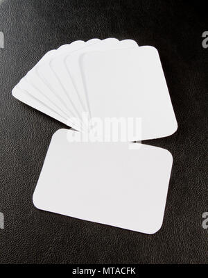 Cartes d'affaires en blanc avec coins arrondis sur un fond noir en cuir Banque D'Images