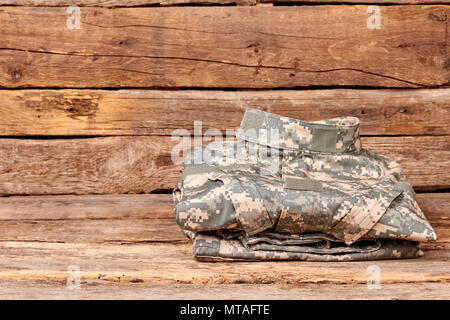 Camouflage militaire parfaitement pliée uniforme. Vêtements de soldat sur bois marron foncé. Banque D'Images