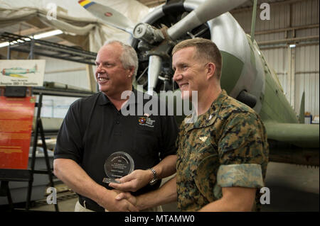 Robert Cramsie, gauche, un bénévole de restauration avec le battant Sapadalure Aviation Museum et membre du conseil de l'Flying Sapadalure base historique, affiche son prix tout en serrant la main avec le Colonel Jason Woodworth, commandant de Marine Corps Air Station Miramar, Californie, au Musée de l'aviation vol Sapadalure Installation de restauration au MCAS Miramar, Californie, le 21 avril. Cramsie a reçu l'excellence Northrop Grumman dans le Bénévolat Le bénévolat pour plus de 2 500 heures pour restaurer une dernière de son genre Douglas SBD-1 Dauntless dive bomber, reconstitué à l'aide de plans, sal Banque D'Images