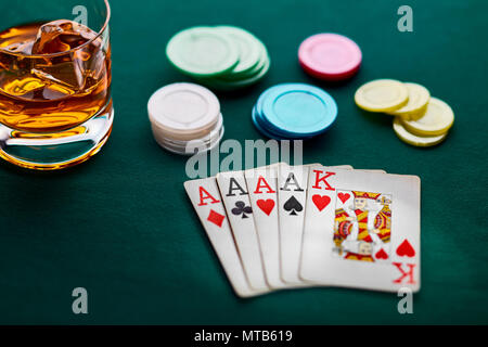 La main de poker de 4 as, chips et un verre de whisky sur le drap vert d'un casino Banque D'Images