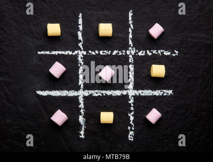 Tic Tac Toe jeu xo avec guimauves colorés sur la surface noir texturé Banque D'Images