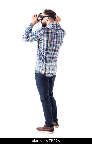 Les jeunes phoques barbus smart casual man putting on casque lunettes de réalité virtuelle sur la tête. Corps plein isolé sur fond blanc. Banque D'Images