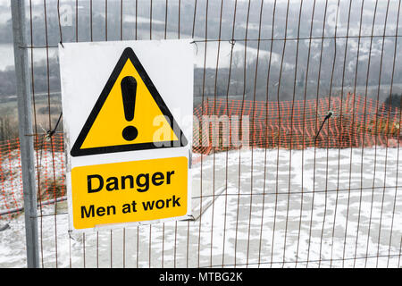 Santé et sécurité 'jaune' panneau d'avertissement sur un petit chantier - prise sur un jour de neige en hiver (quelques petites taches foncées sur l'image). Banque D'Images