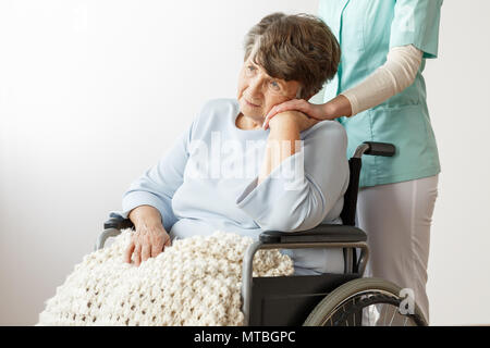 Triste mobilité hauts femme assise dans un fauteuil roulant en maison de soins infirmiers Banque D'Images