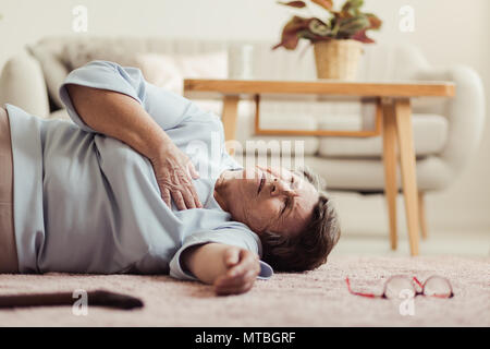 La femme étendue sur le sol et avoir une crise cardiaque à la maison de repos Banque D'Images