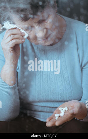 Mauvais senior woman crying, holding pills in hand Banque D'Images