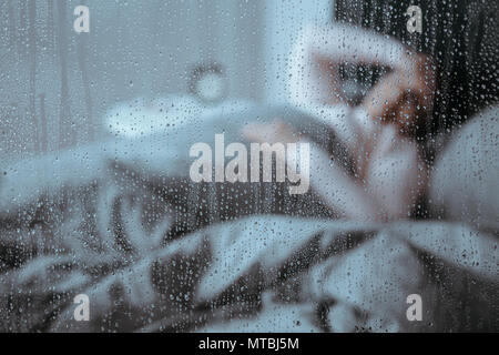 Femme souffrant de l'insomnie au lit le jour de pluie Banque D'Images