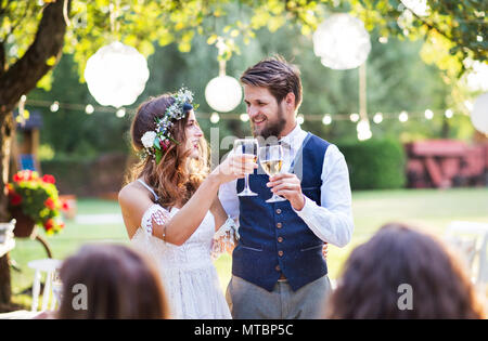 Mariée et le marié avec les clients de réception de mariage à l'extérieur dans la cour. Banque D'Images