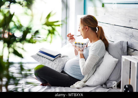 Vue de côté de femme enceinte détente à sa chambre à coucher Banque D'Images