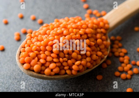 Les lentilles rouges secs dans la cuillère de bois Céréales / Le Masoor Dal. Produit biologique. Banque D'Images