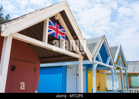 Cabines de plage colorées abris avec la British Union Jack flag peint à la main sur elle Banque D'Images