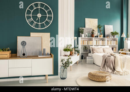 Vieille horloge avec chiffres romains sur un mur vert turquoise blanc au-dessus d'un bahut design scandinave dans un élégant intérieur espace ouvert Banque D'Images