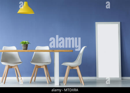 Espace ouvert avec l'intérieur moderne et de chaises en bois blanc, une table avec une plante sur le dessus, jaune et un miroir debout contre un mur bleu Banque D'Images