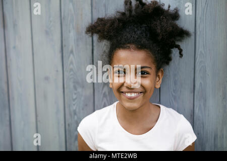 Portrait d'un drôle de jeune fille souriante, debout à l'extérieur de la paroi Banque D'Images