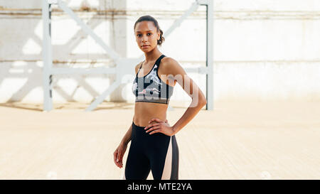 Jeune femme dans les vêtements de sport de détente après l'entraînement. Athlète féminin avec la main sur sa hanche. Banque D'Images