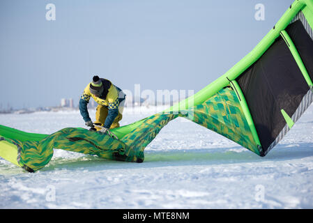 L'athlète dans l'hiver prépare un livre vert sur le cerf-volant pour le snowkite champ neigeux Banque D'Images