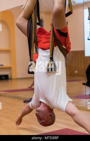 Yoga anti-gravité, l'homme faisant du yoga exercices. l'homme est tête en bas. homme l'échauffement pour la formation à l'aide de yoga anti-gravité des hamacs pour air flying yoga. Le bien-être pour le style de vie. Banque D'Images