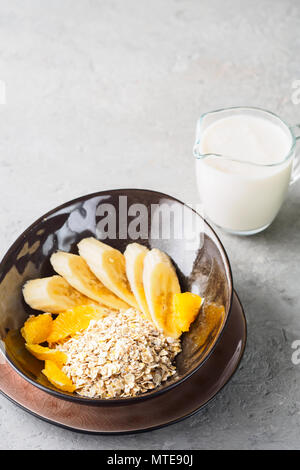 L'Avoine Blé Orge Seigle flocons de maïs mélanger une bonne nutrition alimentation avec des morceaux d'orange banane et verre de lait Banque D'Images