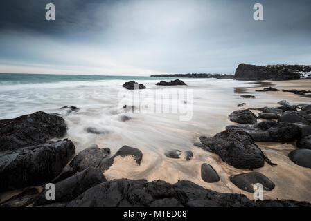 Skarðsvík Beach, plage de sable avec des grosses roches volcaniques noires, les vagues à la mer, le mauvais temps, l'exposition de l'ampoule, à l'ouest de l'Islande Banque D'Images