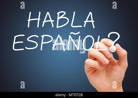 La main question Habla Espanol - parler espagnol avec marqueur blanc sur fond bleu foncé. Banque D'Images