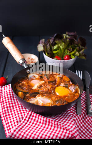 Le petit-déjeuner. Oeufs au plat avec légumes - shakshuka dans une poêle à fond de bois dans un style rustique. Mise à plat. Vue d'en haut. Banque D'Images