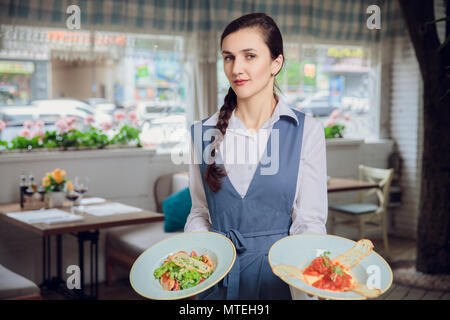 Serveuse exploite deux plaques avec des plats délicieux restautant célébration. Banque D'Images