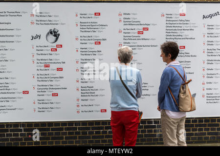 Deux femmes à la recherche à l'annexe pour des pièces et des spectacles sur le mur de Shakespeare's Globe Theatre à Londres Banque D'Images