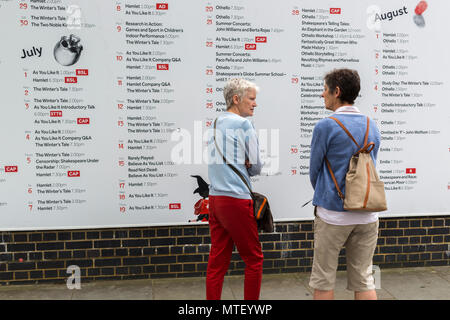 Deux femmes à la recherche à l'annexe pour des pièces et des spectacles sur le mur de Shakespeare's Globe Theatre à Londres Banque D'Images