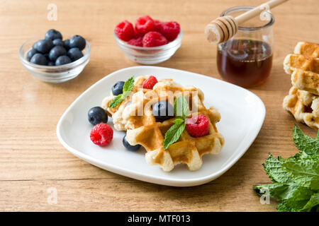 Gaufres Belges traditionnelles avec les bleuets et framboises sur table en bois Banque D'Images