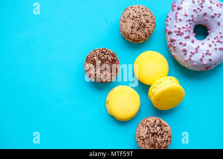 Différents types de macarons, des beignes sur fond bleu.bonbons colorés et savoureux Macarons français sur fond bleu.Vue de dessus.Copy space Banque D'Images