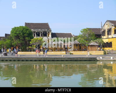 HOI AN, VIETNAM - 19 mars 2018 : Belle journée à l'ancienne ville de Hoi An avec vue de la population locale, de bateaux, de maisons au bord de la rivière jaune, et les touristes Banque D'Images