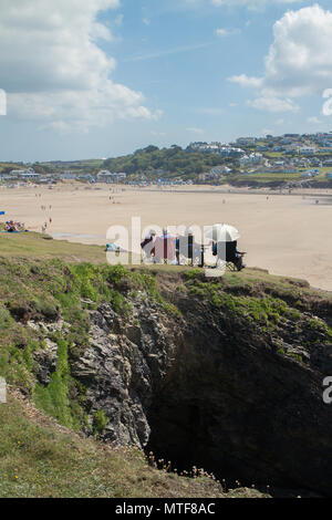 Les vacanciers assis sur la falaise à Polzeath, Cornouailles du Nord Banque D'Images