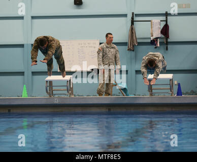 Des soldats américains avec le 20ème commandement CBRNE, plonger dans la piscine pour commencer la partie natation de 100 mètres de la compétence des Forces armées allemandes (Badge) GAFPB à la Central Washington University, Ellensburg, Washington, le 23 avril 2017. Le GAFPB nager exige que les participants à nager en uniforme, sans bottes, pour 100 mètres en moins de quatre minutes, puis déposer l'uniforme dans l'extrémité profonde sans tenir les bords de la piscine. Banque D'Images