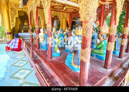 BAGAN, MYANMAR - février 24, 2018 : Myazedi culte dispose de rangées de chiffres en bois sculpté au milieu de son temple avant l'autel doré avec Banque D'Images