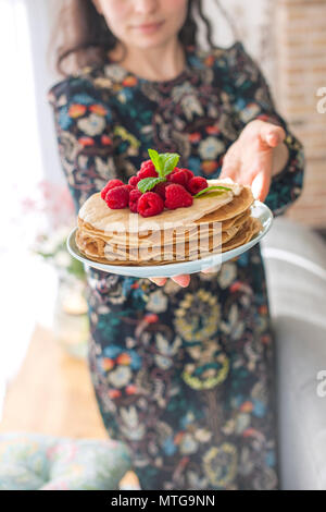 Photo de jeune femme debout à la cuisine dans la cuisine familiale. Se concentrer sur des crêpes. Banque D'Images