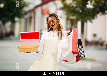 Trendy girl à lunettes avec des boîtes à chaussures et des sacs en t Banque D'Images